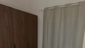 Makuuhuone, jossa on sänky, puinen vaatekaappi ja verho.