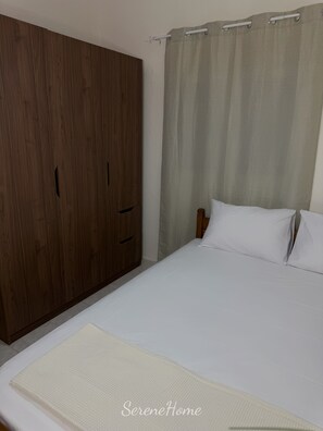 A bedroom with a bed, a wooden wardrobe, and a curtain. - SereneHome 700m from the beach (Kallikrateia)
