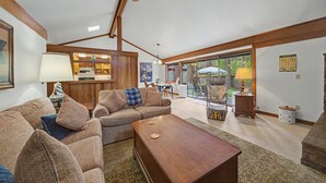 A spacious living room with a wooden ceiling fan, a sofa set, a dining table, and a kitchen area visible through a sliding glass door. - Pet friendly, fully fenced, A/C (Graeagle)