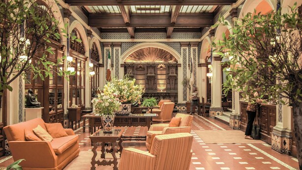 An interior with arched ceilings, wooden furniture, and a central floral arrangement.