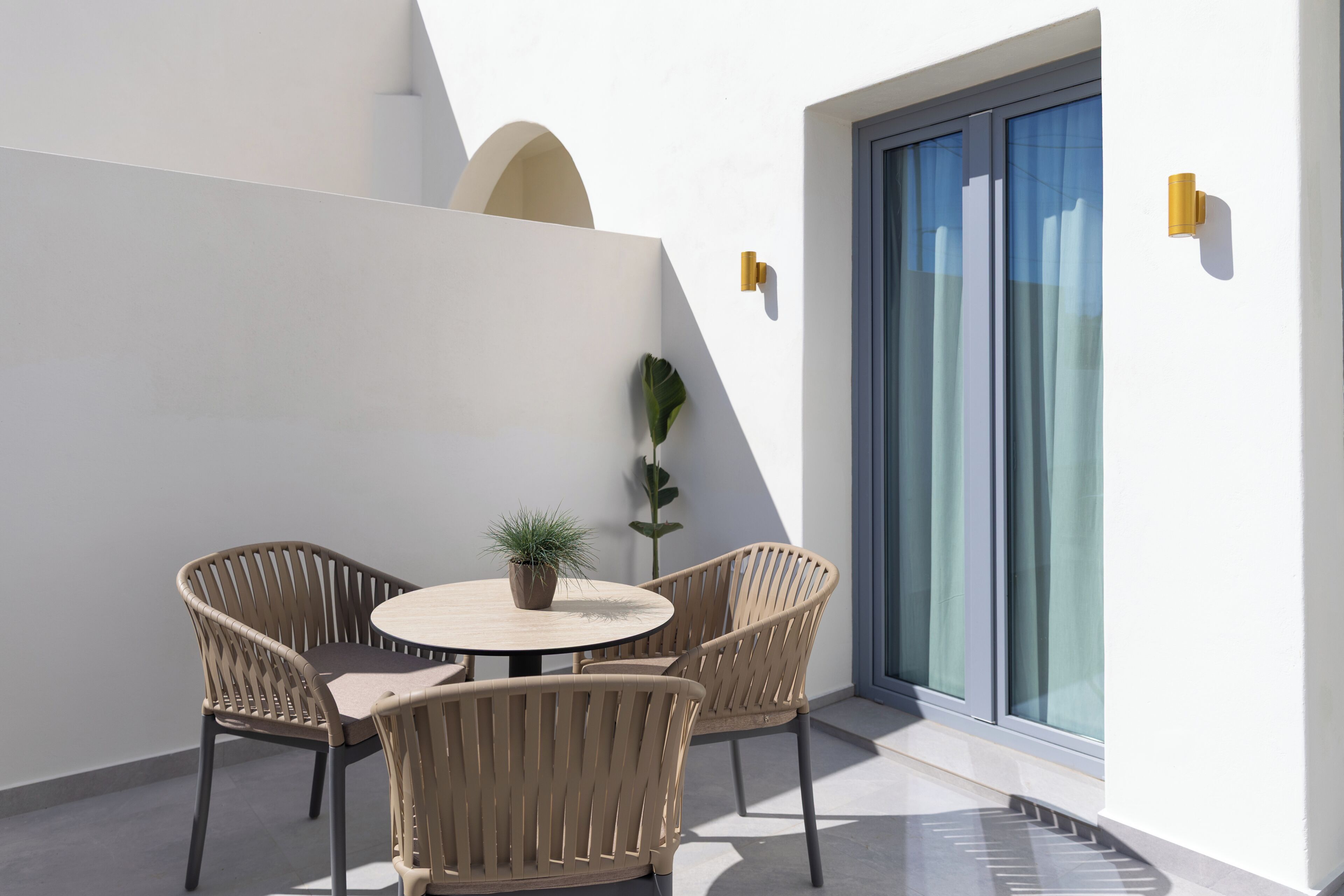 A modern outdoor seating area with wicker chairs, a round table, and a potted plant.