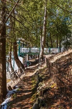 A forested area with a wooden walkway, a bridge, and a stone wall.
