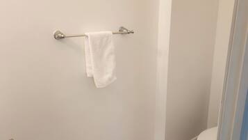 Een badkamer met een wit toilet, een handdoek aan een metalen handdoekhouder en een marmeren vloer.