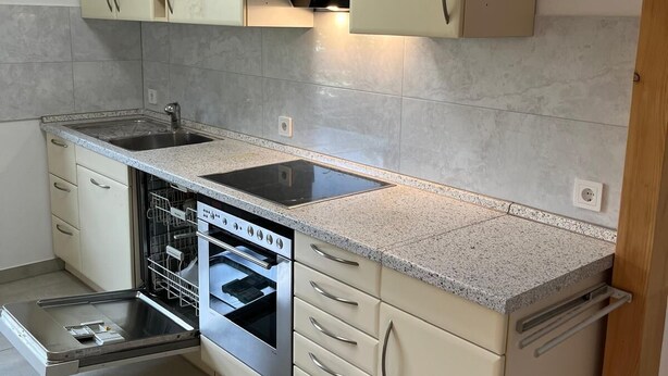 A compact kitchen with a built-in dishwasher, a stove, and a sink. - Sindel Living Apartment-Freshly renovated 2-bedroom apartment with floor heating (Sindelfingen)
