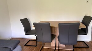 A dining area with a wooden table and two black chairs with metal frames. - Sindel Living Apartment-Freshly renovated 2-bedroom apartment with floor heating (Sindelfingen)