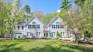 A two-story house with a symmetrical facade, large windows, and a well-maintained lawn. - Wild, Wild West Side! Hot tub, Games, Dog Friendly (Conway)