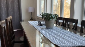 A dining table with a woven placemat, chairs, and a potted plant.