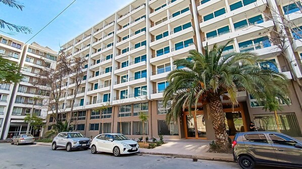 A multi-story residential building with balconies, parked cars, and palm trees. - Movistar Arena Santiago - Domus Travels (Santiago)