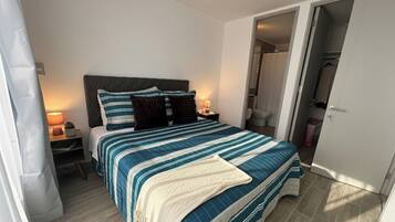 Un dormitorio con cama, mesitas de noche, lámpara y armario.