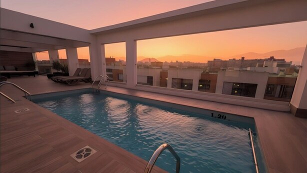 A rooftop pool with clear views of the city skyline and mountains at sunset. - Movistar Arena Santiago - Domus Travels (Santiago)
