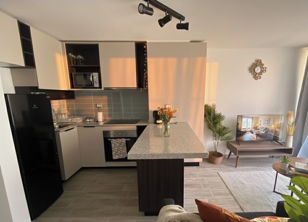 A modern kitchen with a central island, built-in appliances, and a dining area with a TV.