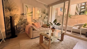 A modern living room with a sofa, a glass coffee table, and large windows. - Movistar Arena Santiago - Domus Travels (Santiago)