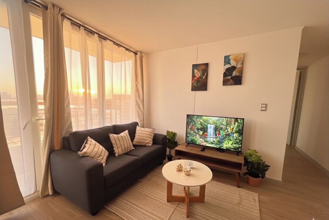 A living room with a sofa, a coffee table, a TV, and two wall art pieces.