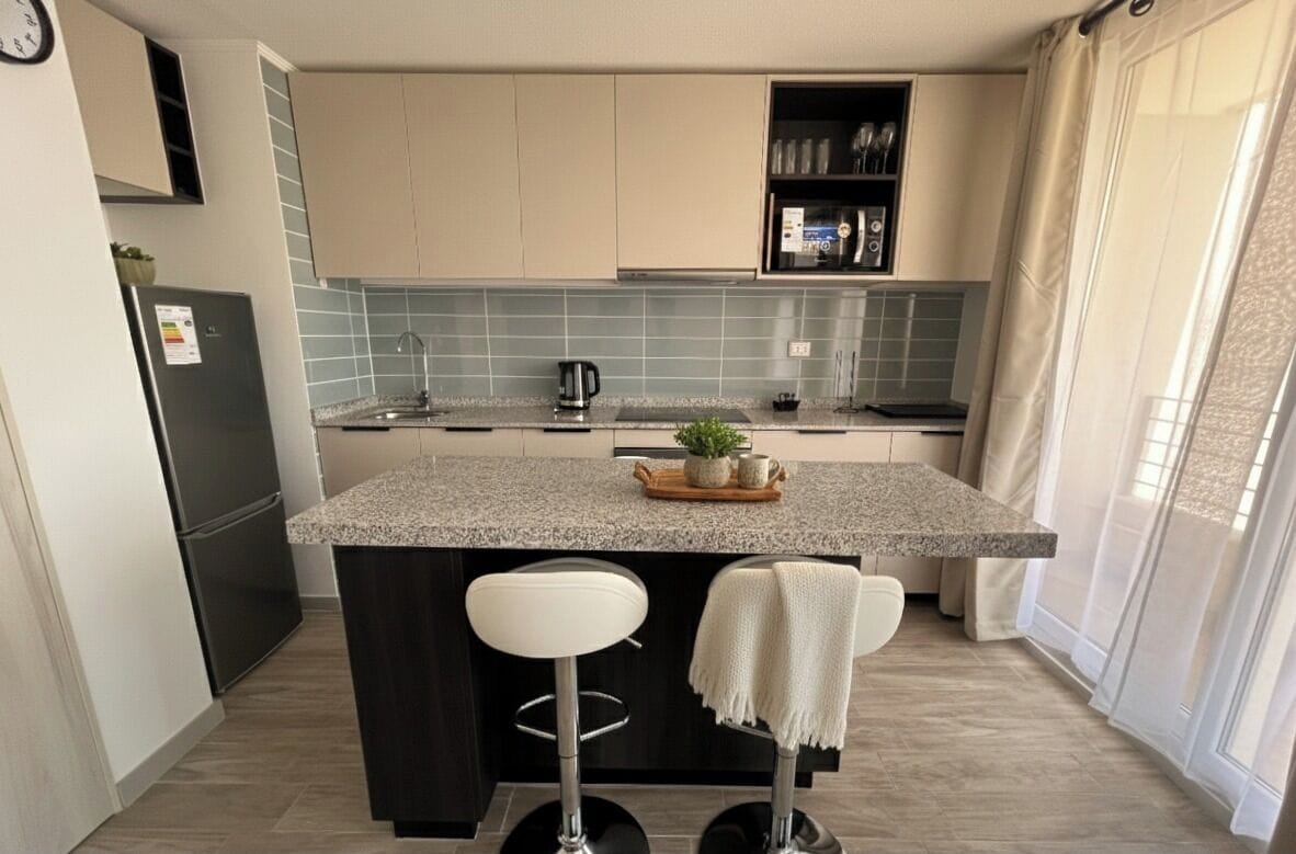 A modern kitchen with a central island, bar stools, and a built-in oven.