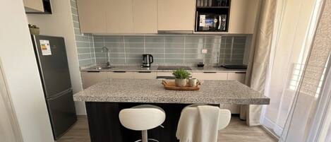 A modern kitchen with a central island, bar stools, and a built-in oven.