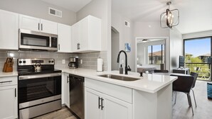 Una cocina moderna con armarios blancos, electrodomésticos de acero inoxidable y una isla grande con fregadero.