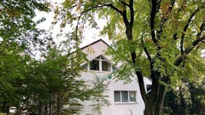 A white building with a sloped roof and a large tree in front. - Silvio-Gesell-Tagungsstätte (Wuppertal)