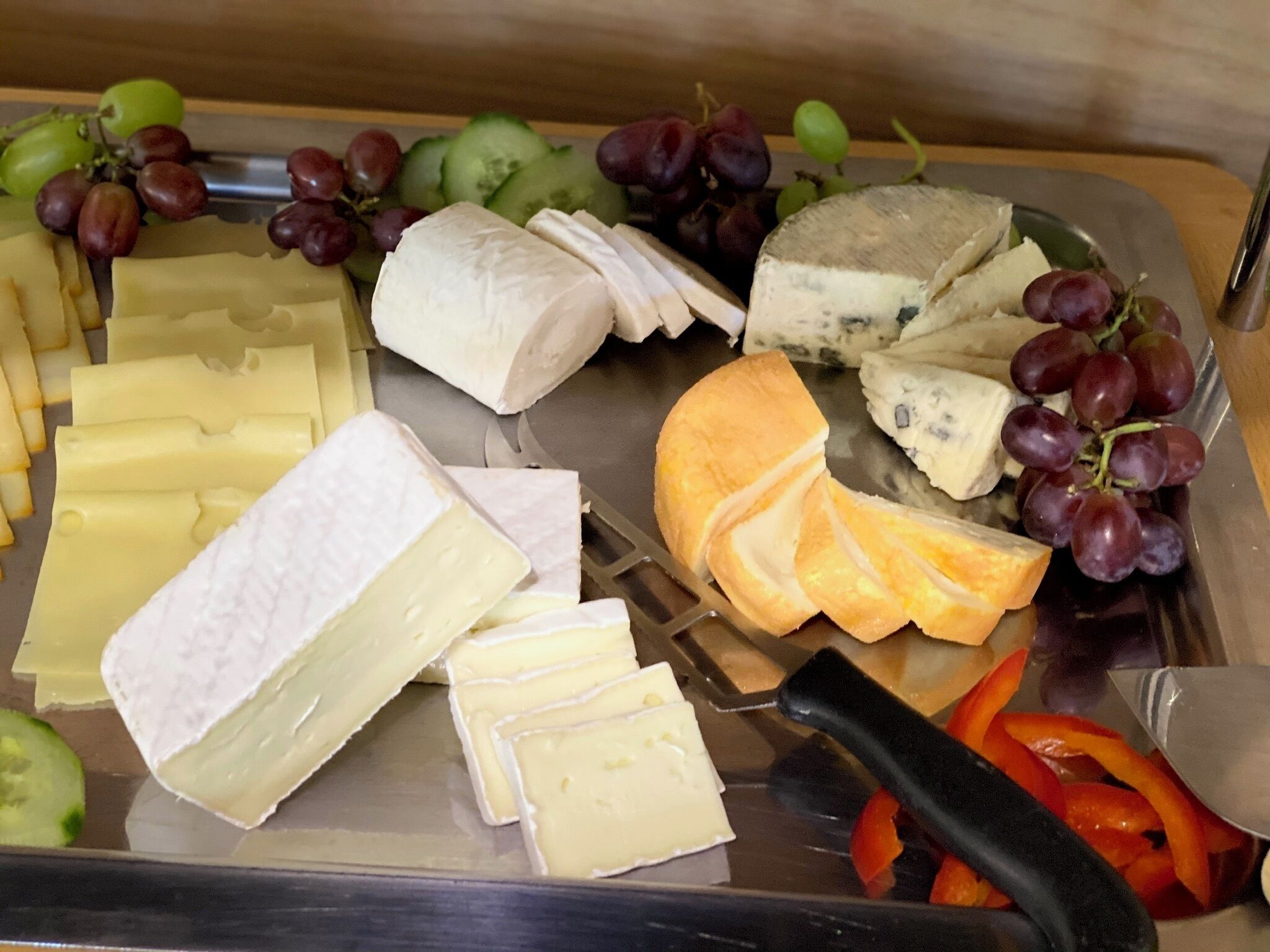 A cheese and fruit platter with various cheeses and grapes.