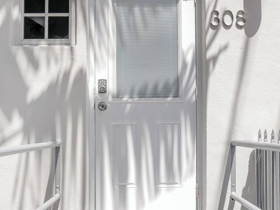 Puerta blanca con una ventana encima y el número '608' en la pared a la derecha.
