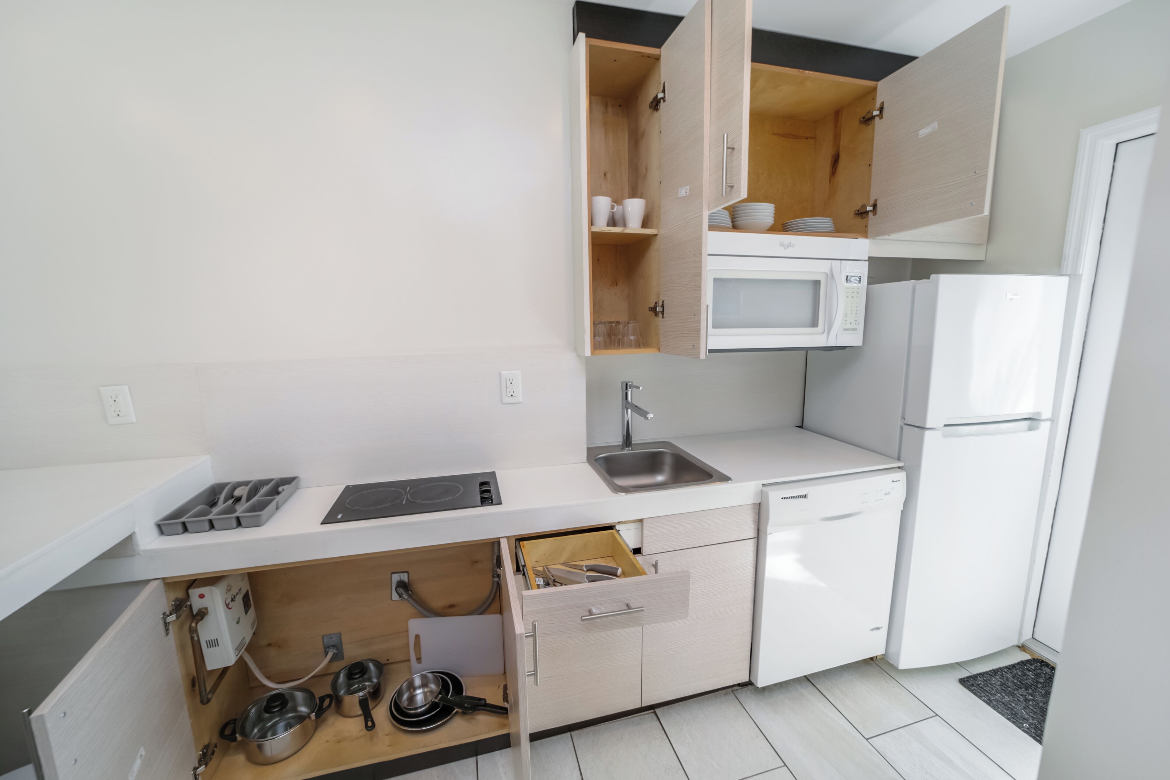 A compact kitchen with a microwave, sink, and built-in oven.