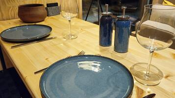 A wooden table with a blue plate, a wine glass, and a bowl.