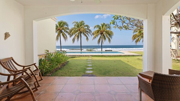 Eine Terrasse mit Blick auf den Ozean, Palmen und einen Swimmingpool.