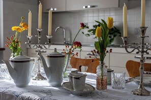 A dining table set with white ceramic teapots, a glass pitcher, and a teacup. There are candles and flowers in glass vases on the table. - Villa of 120 square meters, surrounded by a large garden, equipped and whirlpool spa (Colle di Val d'Elsa)