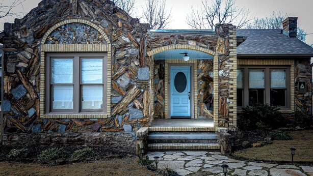 A stone house with a blue door, large windows, and a stone staircase leading to the entrance. - Adorable 3 Bedroom/2 Bath Remodeled Cottage and Carriage House Built Circa 1930! (Glen Rose)