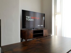 A television on a wooden stand with a Netflix sign on the screen. - Spacious 3BR - Nr Clifton Train Station 510min Walk - Garden & Free Parking (Manchester)