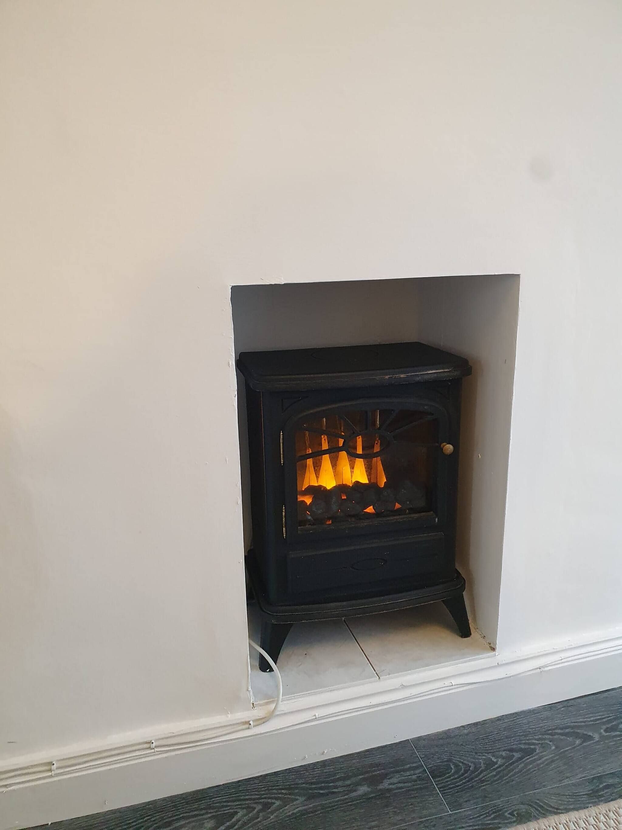 A black wood-burning stove in a white-walled room with a tiled floor.
