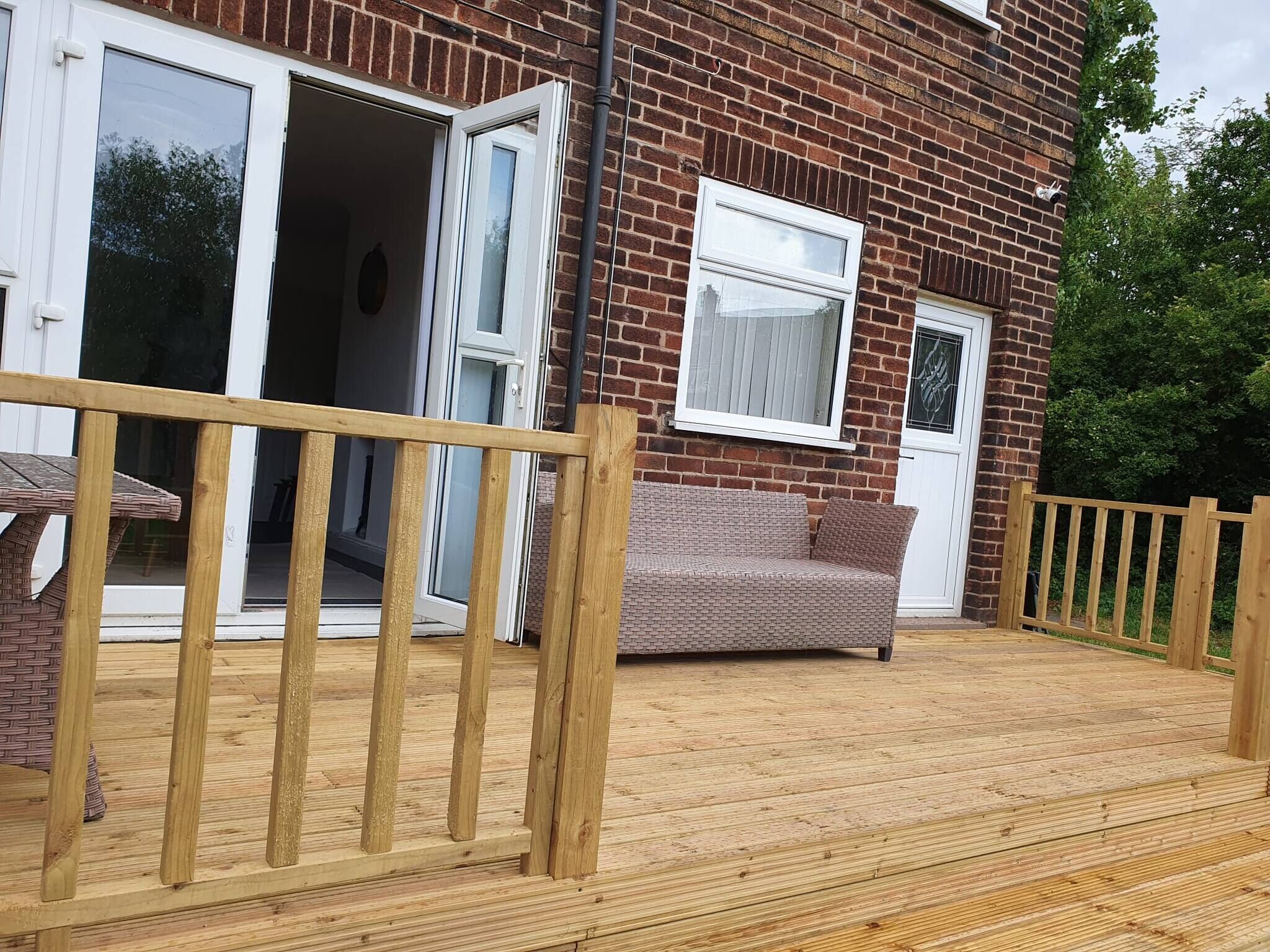 A wooden deck with a wicker table and a cushioned bench.