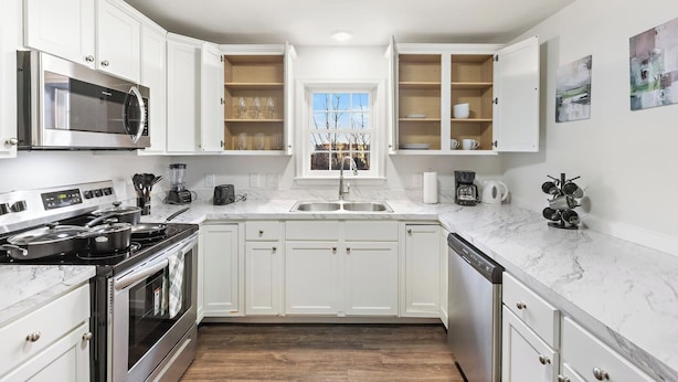 A modern kitchen with white cabinetry, a stainless steel stove, a microwave, and a dishwasher.