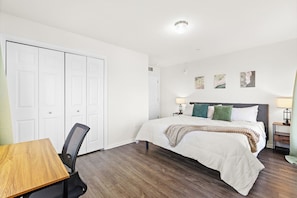 Un dormitorio con cama, mesitas de noche, escritorio y silla.