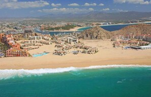 An aerial view of a coastal resort with multiple buildings, a beach, and a rocky outcrop. - Spacious 2BR 2BA Beachfront Walk-Out Condo in Terrasol Resort, Cabo San Lucas (Cabo San Lucas)