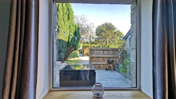 A view through a window with a wooden shelf and a decorative vase. - Comfortable gîte in the heart of the Cotentin region, ideal for families (La Hague)