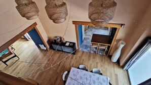 A dining area with a table and chairs, a bar area with a counter and stools, and a hanging light fixture. - Comfortable gîte in the heart of the Cotentin region, ideal for families (La Hague)