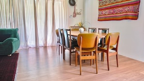 A dining area with a wooden table and chairs, a green armchair, and a striped curtain.