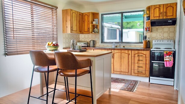 A kitchen with wooden cabinets, a stove, and two bar stools.