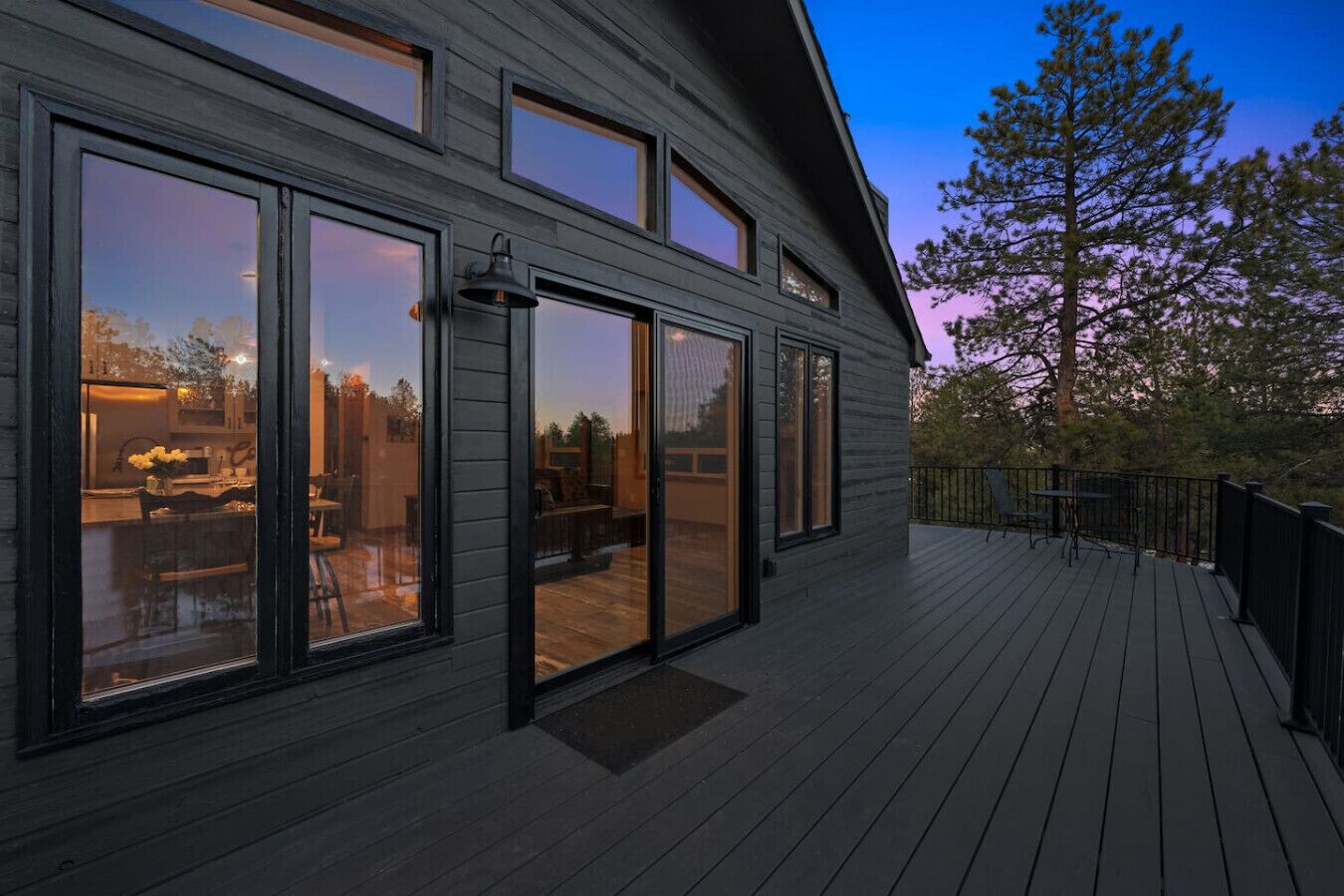 A modern house with large sliding glass doors, a deck, and a view of the outdoors.