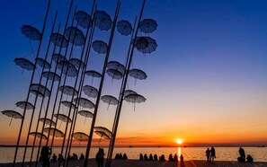 A beach scene with umbrellas and people at sunset. - Le Floor Urban Escape Near Thessaloniki Center (Neapoli-Sykies)