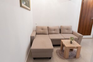 A living room with a sectional sofa, a small wooden table, and a door. - Le Floor Urban Escape Near Thessaloniki Center (Neapoli-Sykies)