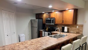 A kitchen with a granite countertop, stainless steel appliances, wooden cabinets, and bar seating. - Beautiful newly decorated 3-bedroom condo with 2 pools in Branson (Branson)