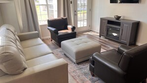 A living room with a sofa, armchair, ottoman, and entertainment unit. - Beautiful newly decorated 3-bedroom condo with 2 pools in Branson (Branson)