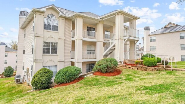 A multi-story residential building with a central staircase, balconies, and a landscaped front yard. - Beautiful newly decorated 3-bedroom condo with 2 pools in Branson (Branson)