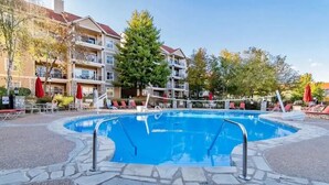 A swimming pool surrounded by lounge chairs and umbrellas, with a multi-story building in the background. - Beautiful newly decorated 3-bedroom condo with 2 pools in Branson (Branson)
