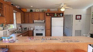 A kitchen with wooden cabinets, a refrigerator, a stove, and a bar area with stools. - 5 Bedroom Quiet Neighborhood Short Walk to Beach (Ocean Isle Beach)