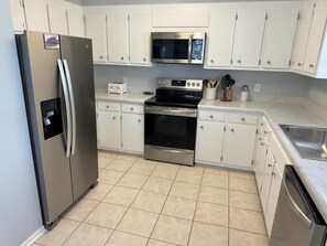 Eine moderne Küche mit weißen Schränken, Edelstahlgeräten, einer Mikrowelle, einem Backofen und einem Geschirrspüler.