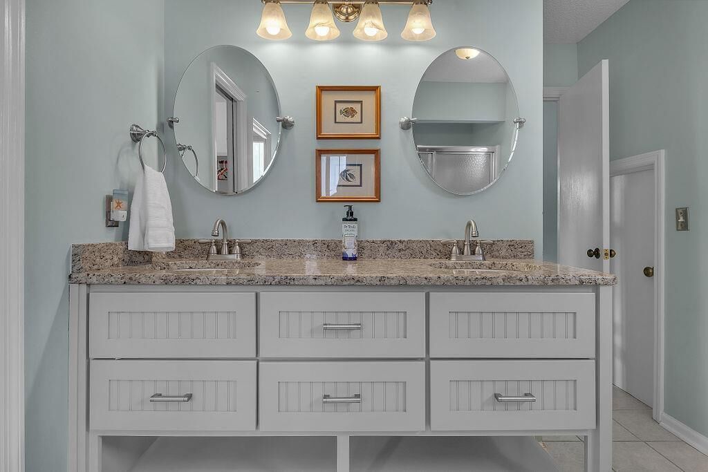 A bathroom with a double vanity, two mirrors, and a light fixture above the sink.