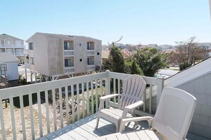 Un balcone con sedie bianche, vista su un edificio moderno e cielo sereno.