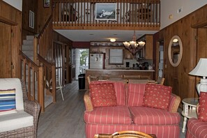 A cozy interior with a staircase leading to a loft, a dining area, and a kitchen. - 4 Bedroom Third Row Cozy Beach Cottage (Ocean Isle Beach)